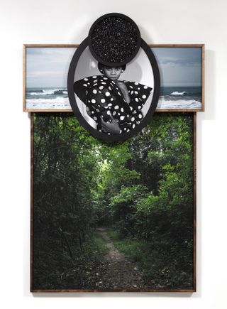 Todd Gray artwork: Four levels of framed photographs are assembled to create a fairly flat sculpture. The largest is of a peaceful green forest with a path down the center. On top covering just the top ¼ of the forest, a panoramic view of waves from a shore. On top, an ovular framed black-and-white photo of a Black woman wearing an angular polka-dotted top. On top, a small circular frame of a starry galaxy.