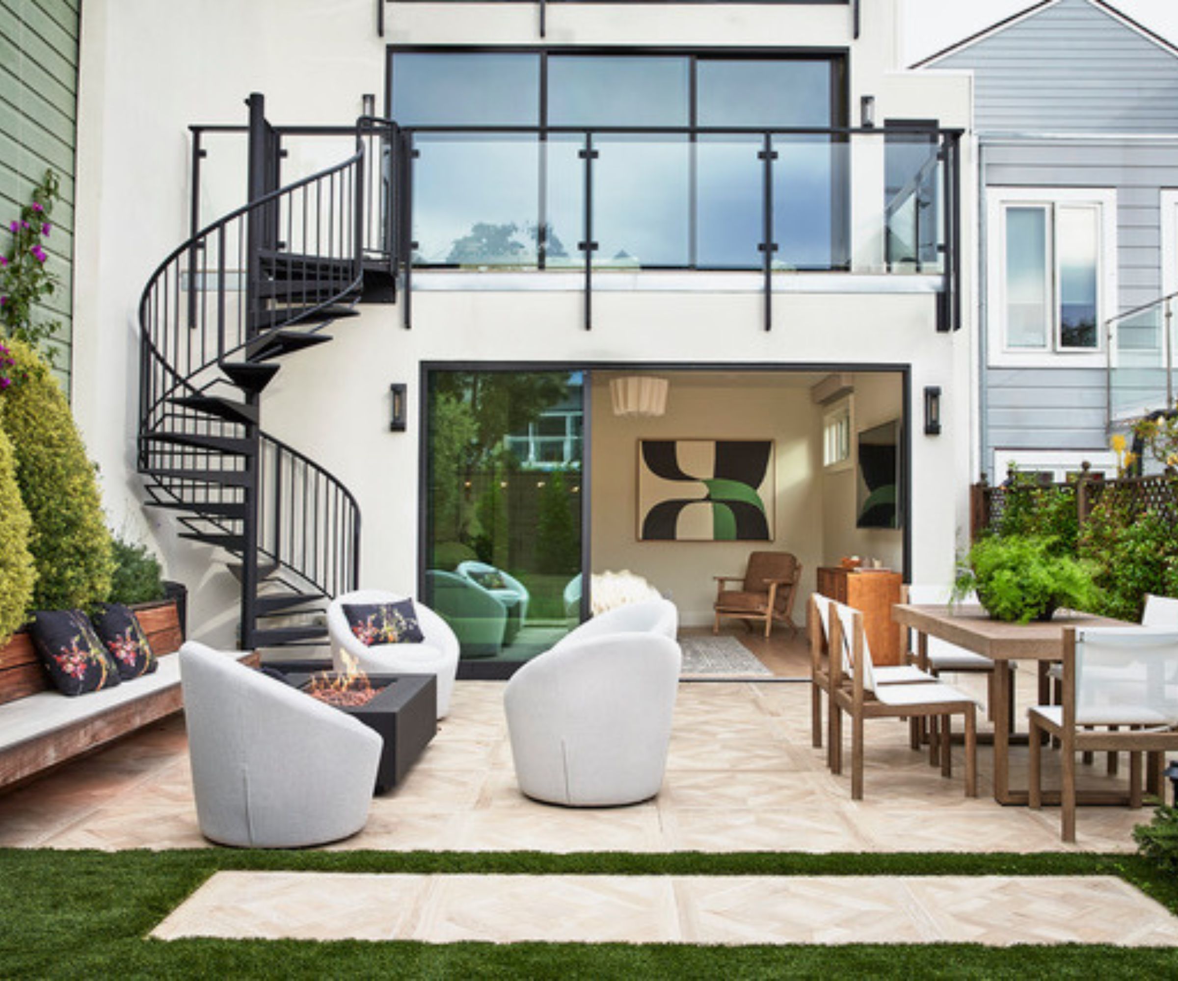 Outdoor seating area with swivel seats, dining table and a balcony with spiral stairs