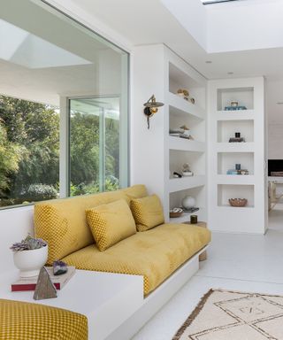 Mandy Moore lounge area with yellow seat, sconce, and white built-in shelves