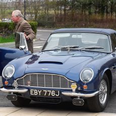 King Charles getting out of his blue Aston Martin 