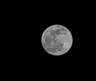 large illuminated full moon against the black backdrop of space.