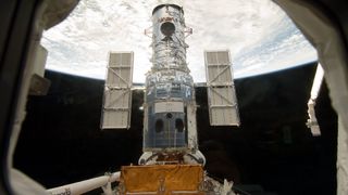 The Hubble Space Telescope stands tall in the cargo bay of the Space Shuttle Atlantis following its capture and lock-down in Earth orbit.