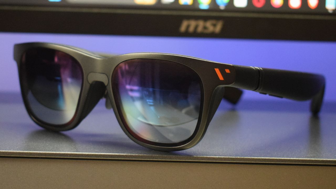 Photo of VITURE Pro XR Glasses on a Hexcal Studio stand with MSI monitor out of focus in background.