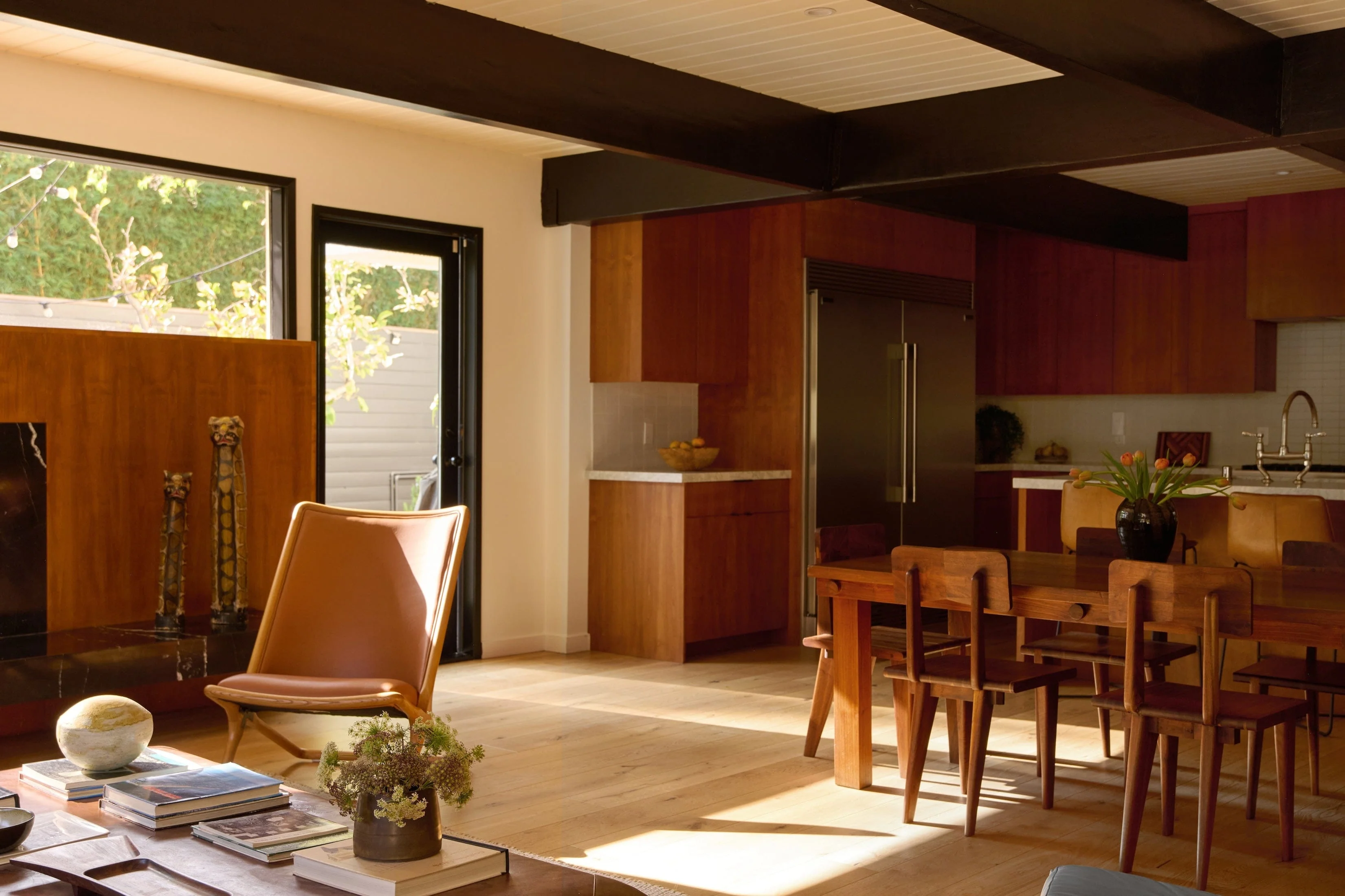 brown wood kitchen cabinets with white counter tops and two door silver fridge. in from is a wooden table with matching wooden chairs.