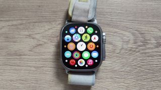 En smartklokke av typen Apple Watch liggende på et trebord.
