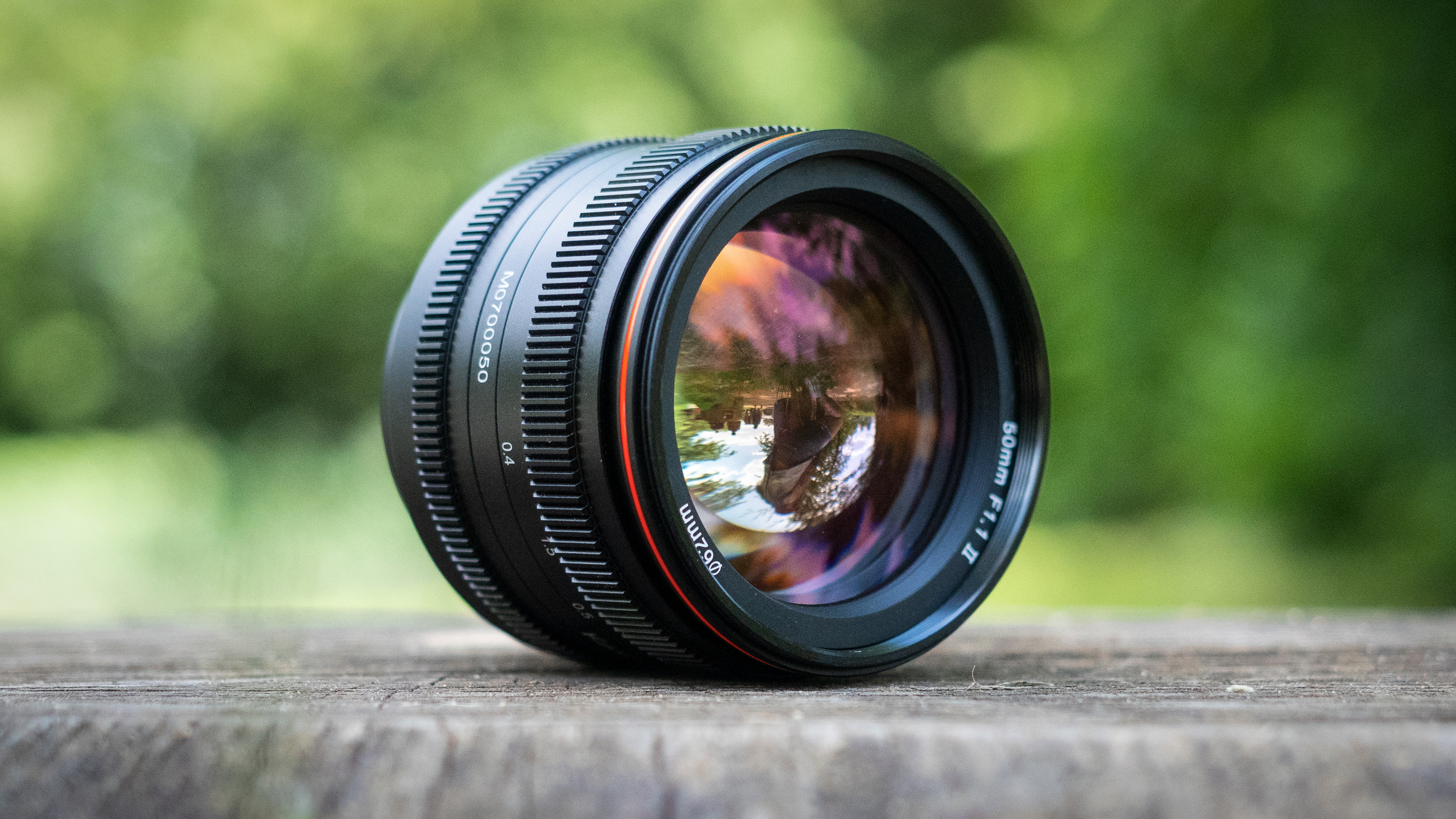 A 50mm f/1.1 lens sat on a wooden surface, outdoors