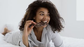 A young woman eats chocolate before bed 