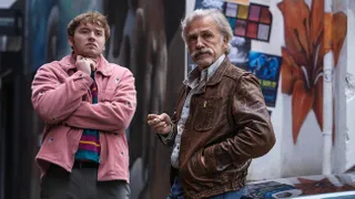 cooper hoffman in a pink jacket crossing his arms and christoph walz in a brown leather jacket in a still from the movie old guy