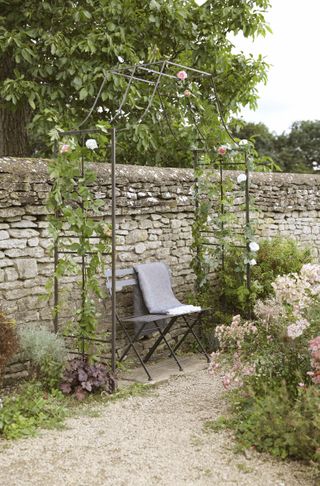 garden bench under rose arch in country garden