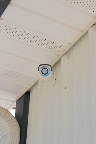 A Snap One white surveillance camera is hung from an eave at the winery.