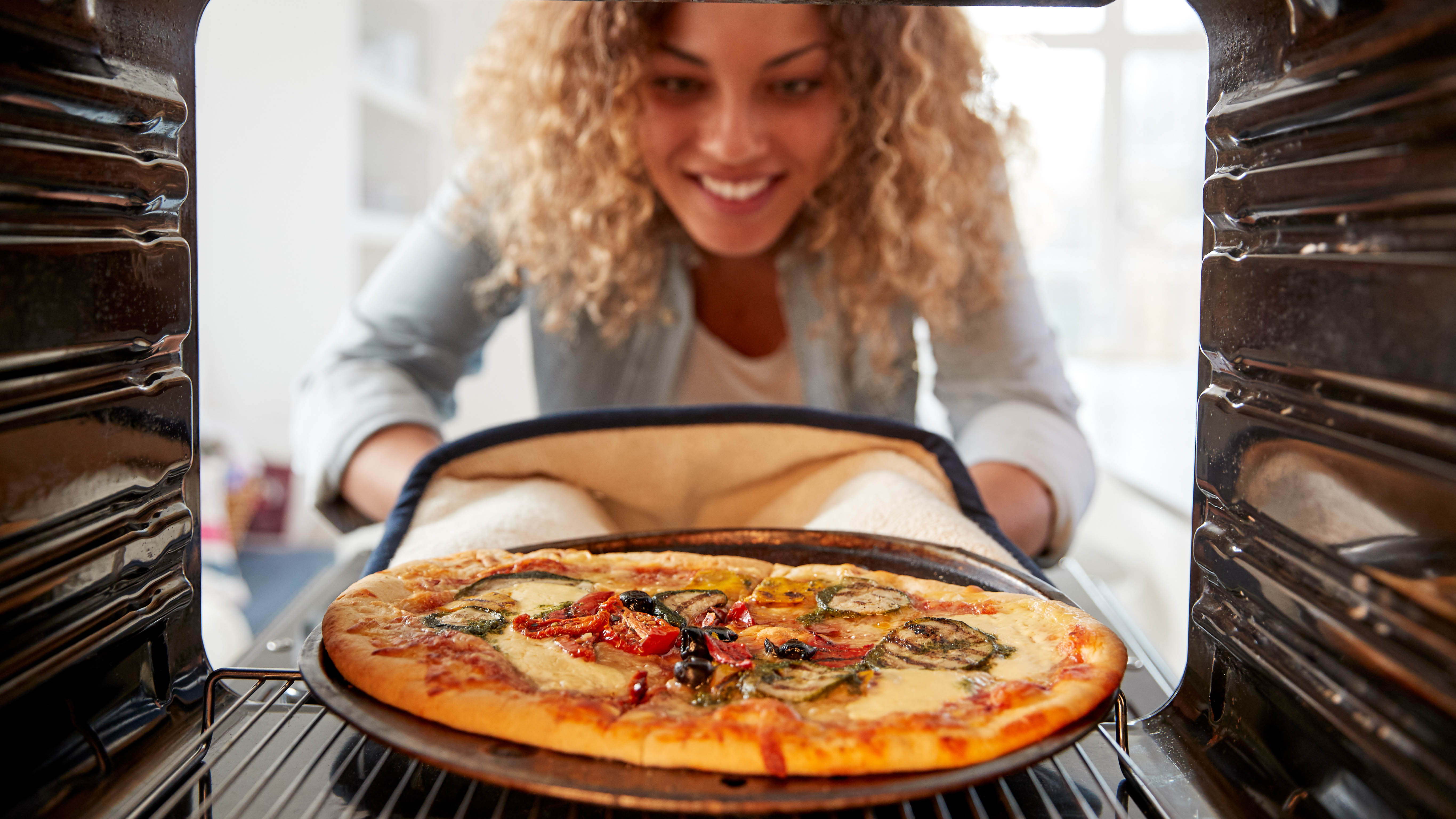 Eine Pizza wird auf einem Blech in den Ofen geschoben