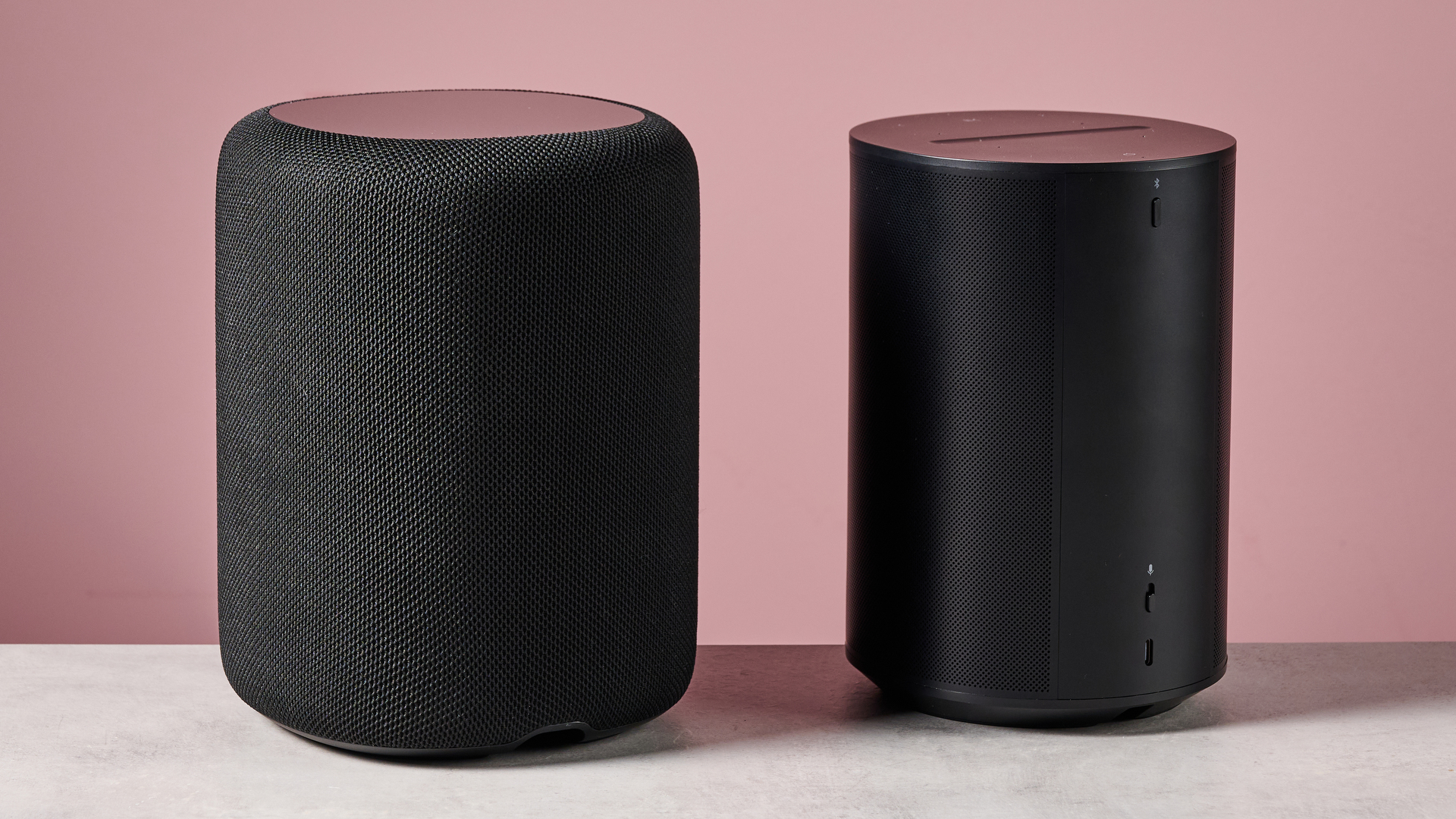 The WiiM Sound Lite side by side with the Sonos Era 100 in front of a pink background.