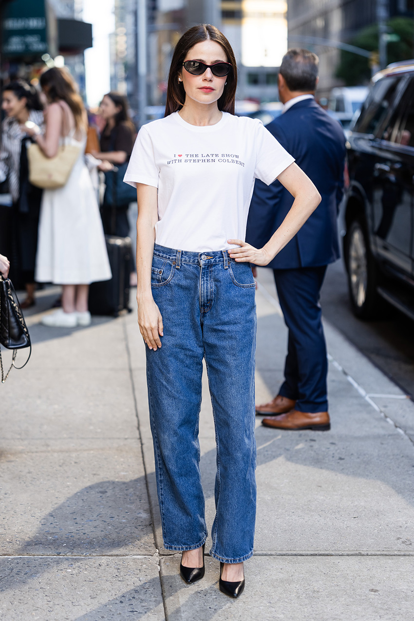 Molly Gordon wearing a white Stephen Colbert T-shirt, jeans, and black pointed-toe pumps in NYC