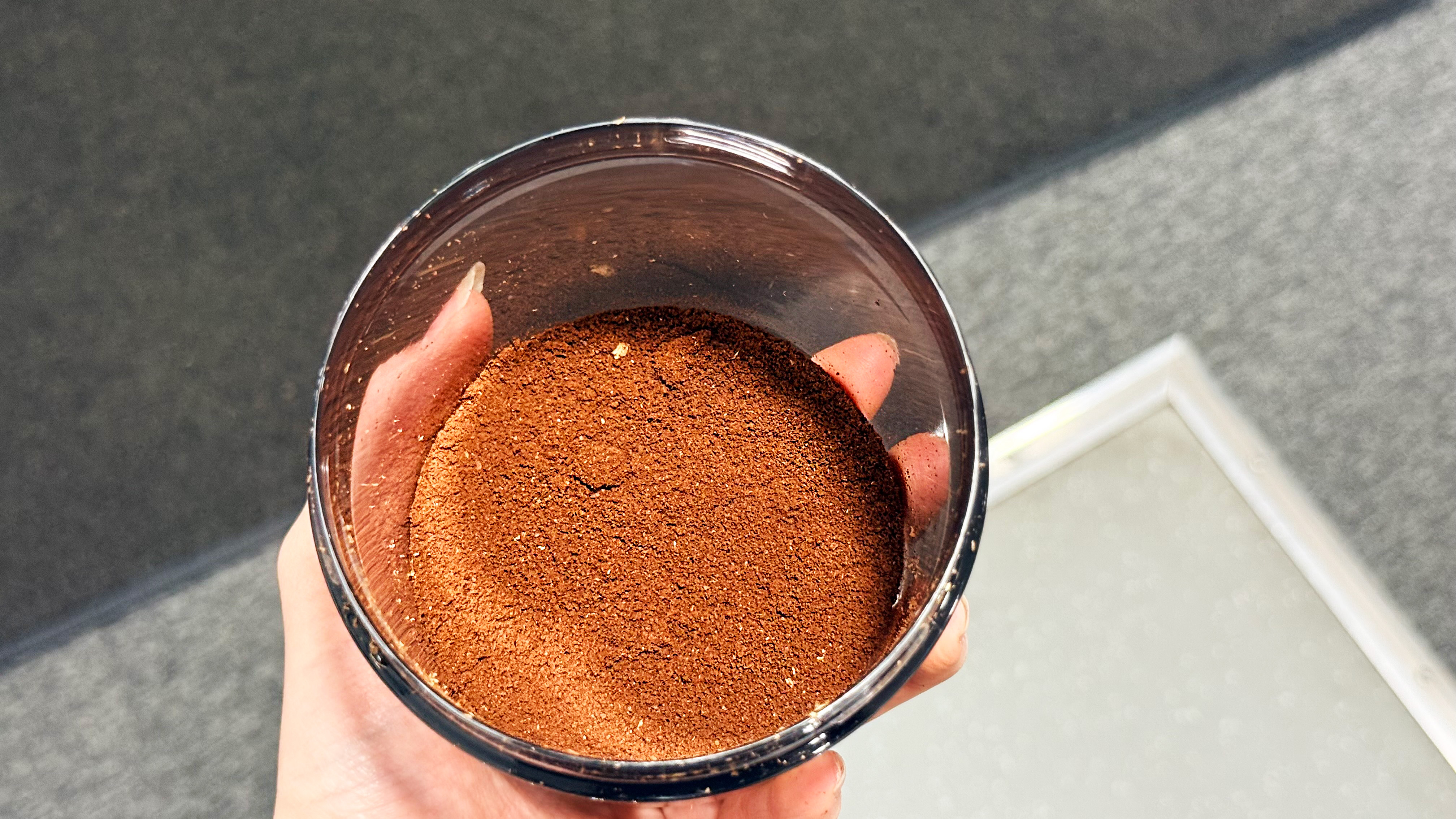 the casabrews tornado grinder results, showing ground coffee in a plastic container