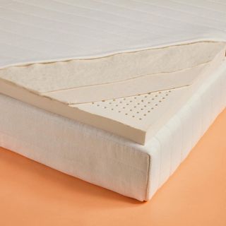 The corner of the Earthfoam Mattress Topper against a peach-colored background.