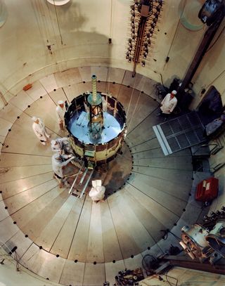 NASA's International Sun-Earth Explorer (ISEE-3) was undergoing testing and evaluation inside Goddard's dynamic test chamber when this photo was taken. Working inside a dynamic test chamber, Goddard engineers wear protective "clean room" clothing to prevent microscopic dust particles from damaging the sophisticated instrumentation. NASA launched the 16-sided polyhedron, which weighed 1,032 lbs. (469 kg.), from Cape Canaveral, Florida, on August 12, 1978.