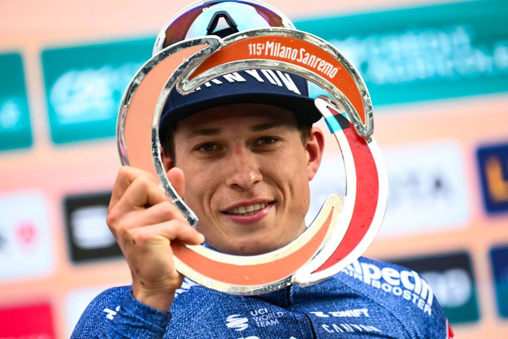 Alpecin-Deceuninck&#039;s Belgian rider Jasper Philipsen celebrates with the trophy on the podium after winning the 115th Milan-SanRemo one-day classic cycling race, between Milan and SanRemo, on March 16, 2024. (Photo by Marco BERTORELLO / AFP)