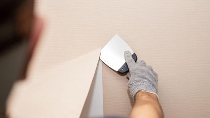 A man removing wallpaper from a wall 