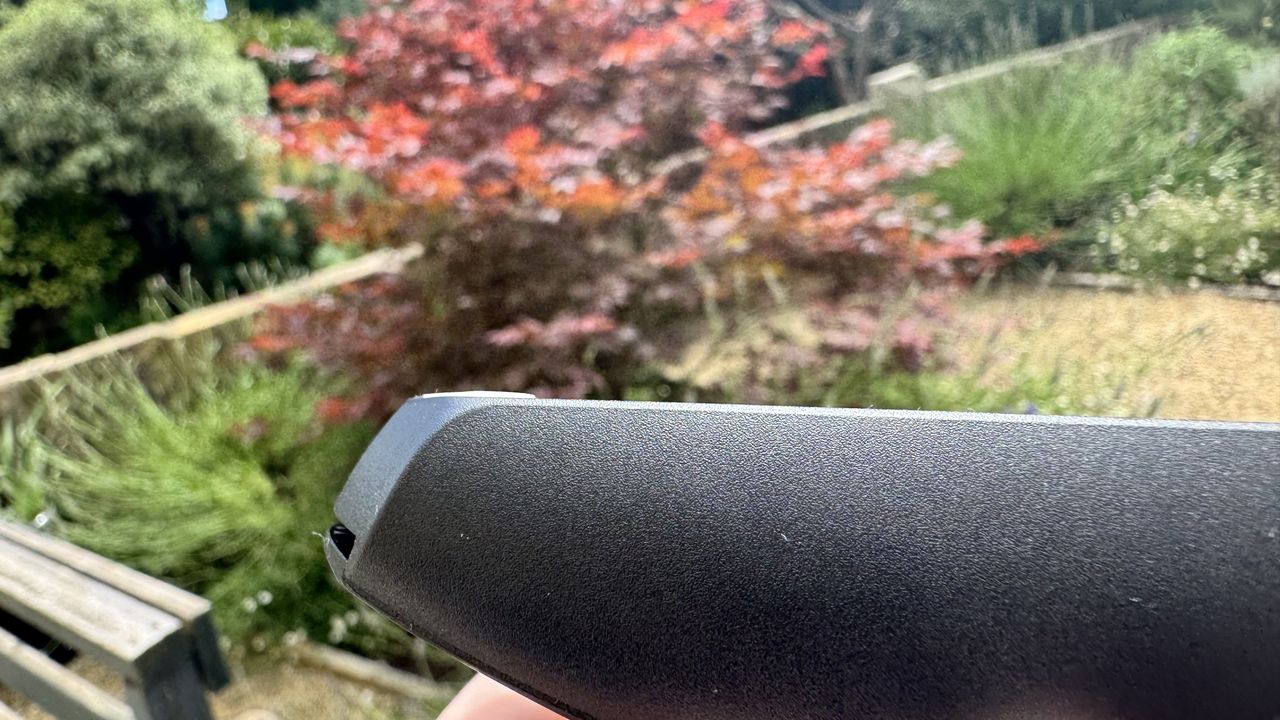 Logitech G305 X Superlight gaming mouse, held in a hand outside