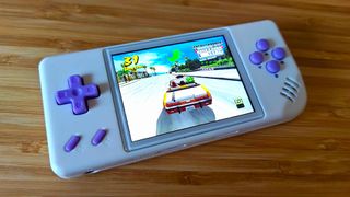 Anbernic RG28XX sitting on woodgrain surface with Crazy Taxi Dreamcast gameplay on screen