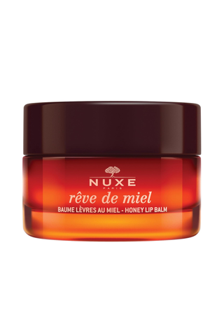 A closed pot of Nuxe Reve de Miel lip balm set against a white background.