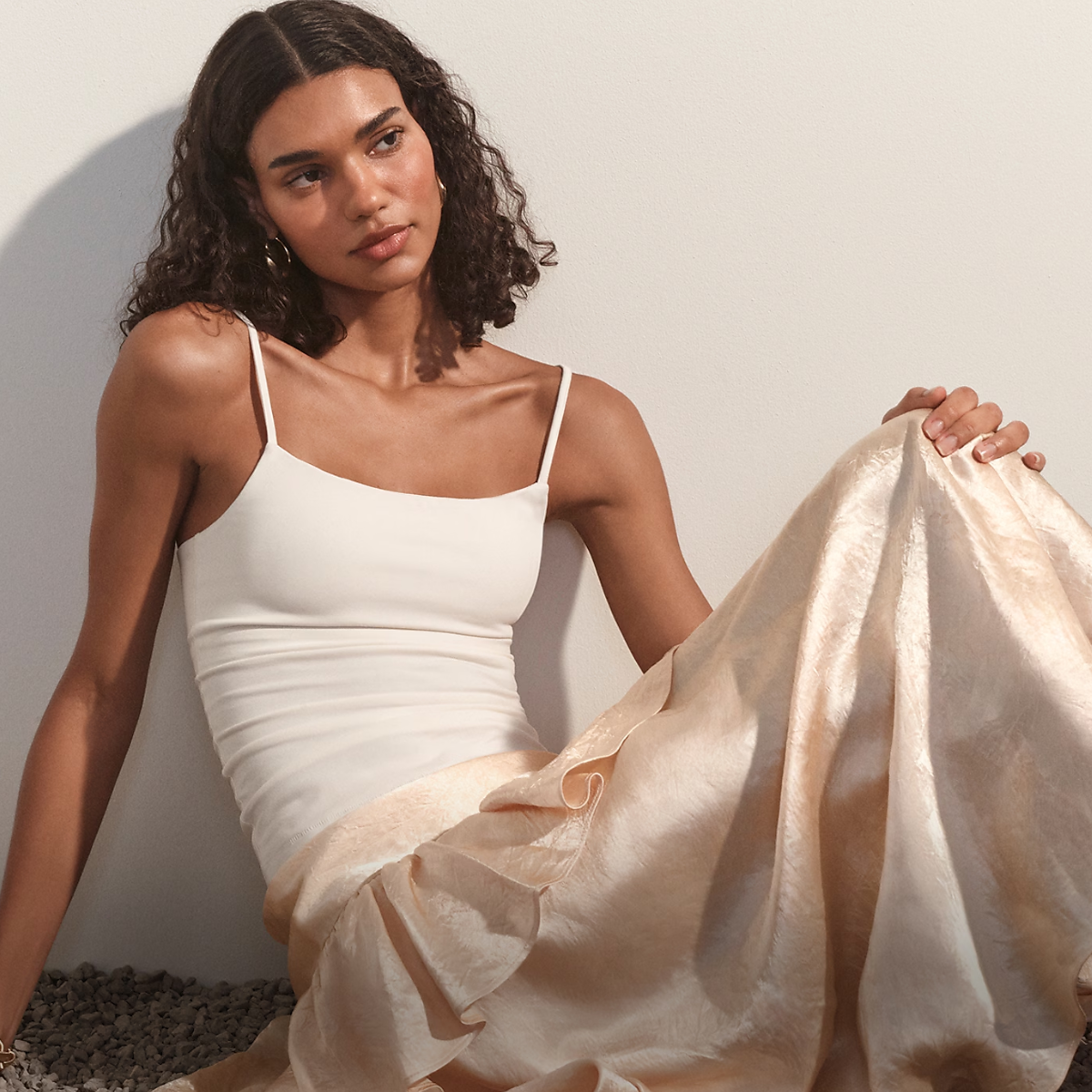 woman wearing a white tank top and gold skirt. 