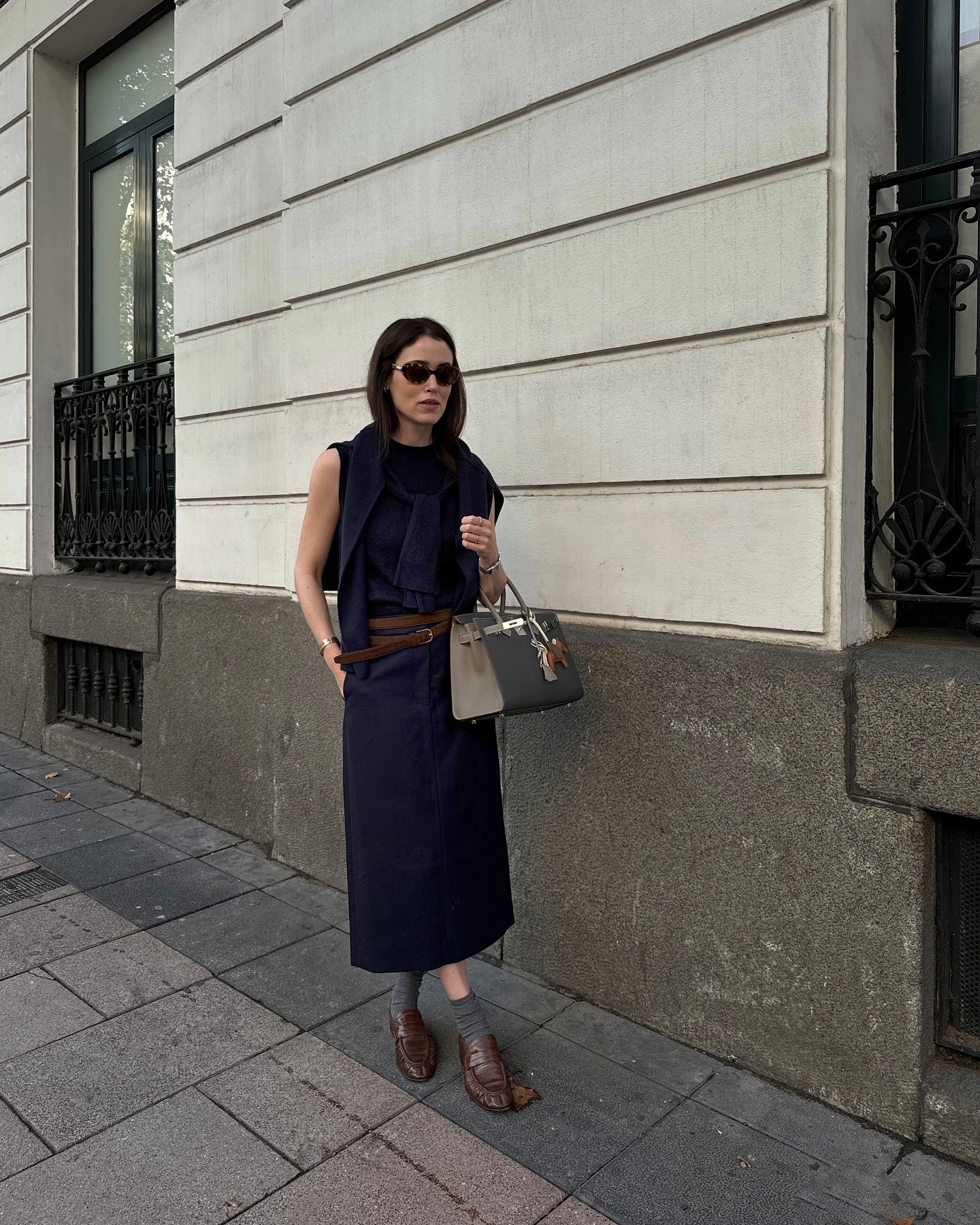 Influencer @annabelrosendahl wears a navy dress with a brown leather belt and brown leather loafers.