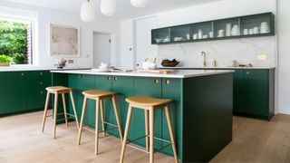 An island in a kitchen with forest green cabinets to illustrate the forest green color trend