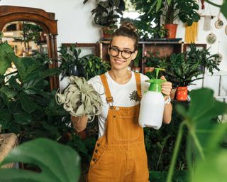young woman misting houseplant