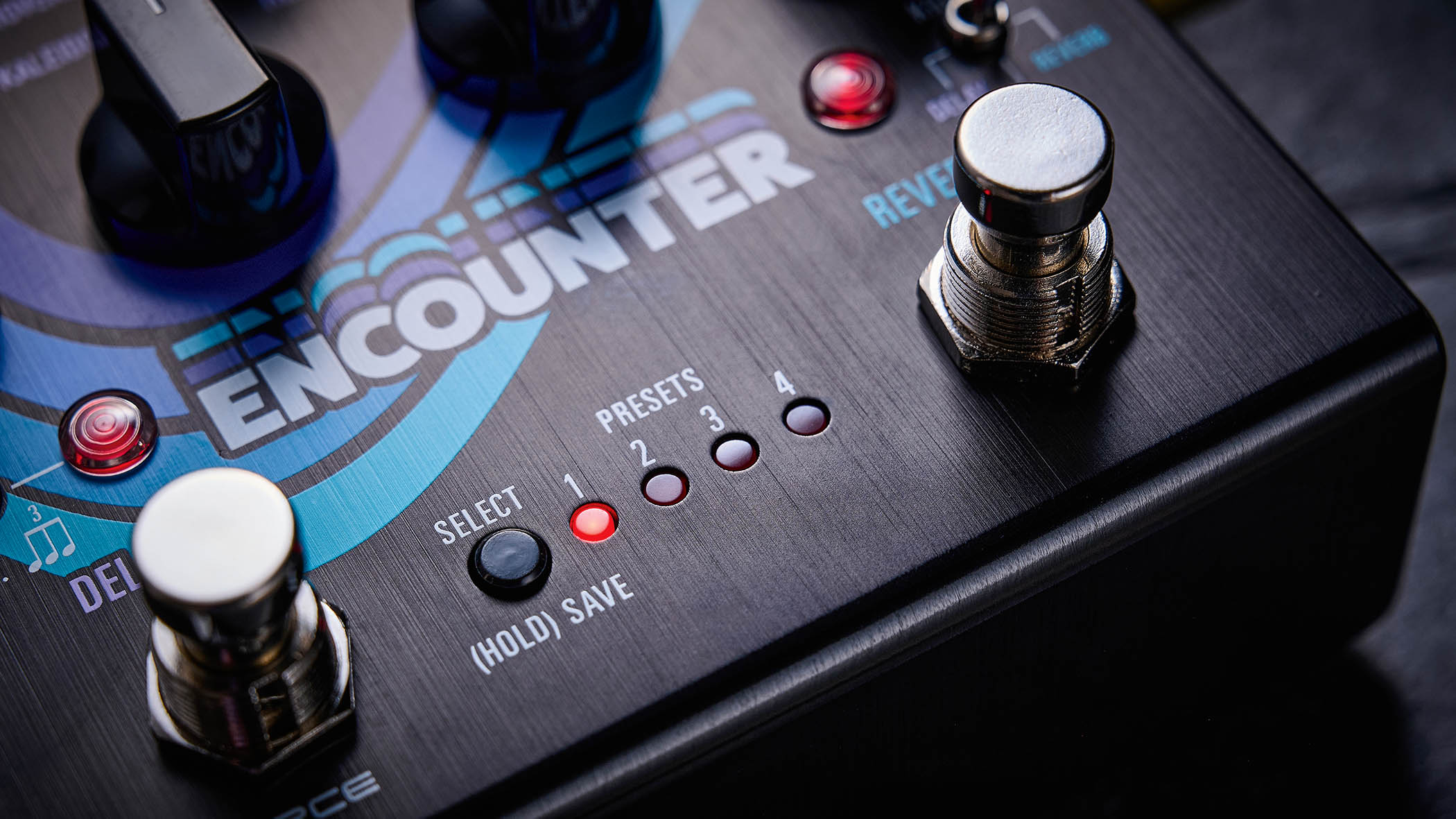 The Source Audio Encounter delay and reverb pedal is photographed here in close-up against an industrial metal background.