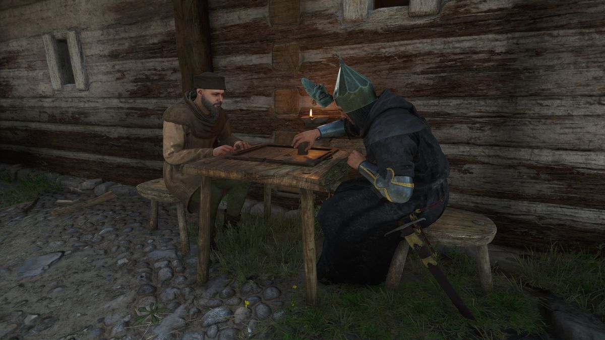 Kingdom Come: Deliverance 2 money - Two people sat at a table playing a dice game next to a wooden building.