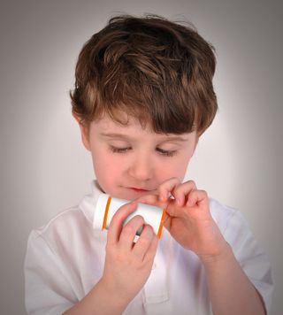 A little boy holds and looks at a bottle of prescription medicine