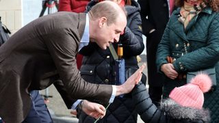 Prince William, Prince of Wales has a high five with young fan Florence Boyle during his visit to The Turf Pub, near Wrexham AFC as he marks St. David's Day on March 01, 2024