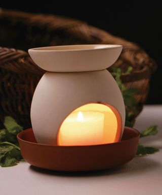 A white oil burner with a tea candle