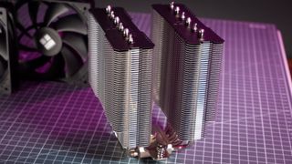 A Thermalright Peerless Assassin 120 SE cooler on a desk with the fans beside it.