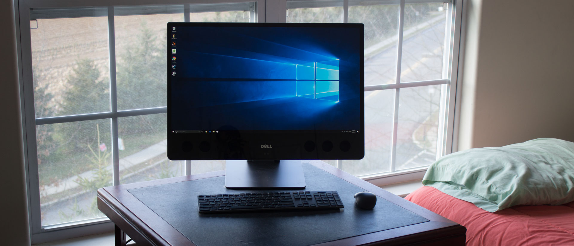 Dell XPS 27 AIO on a table next to a window and a bed