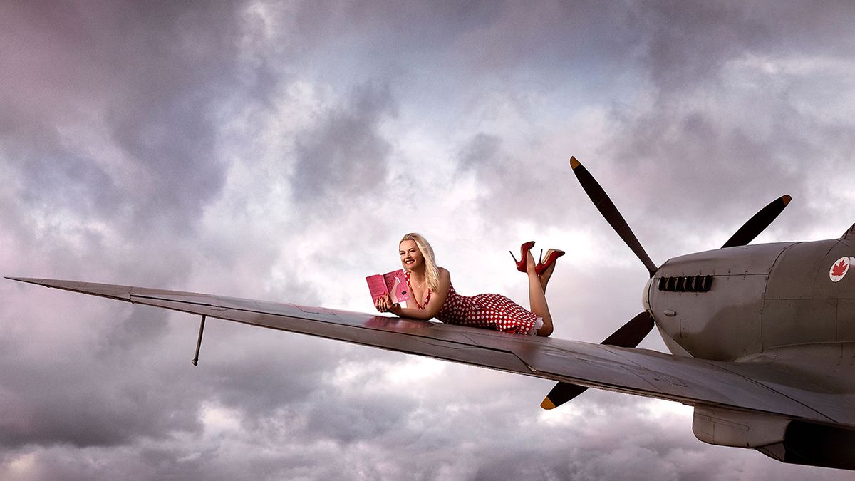 Maggie Robinson reading Shooters on the wing of a plane, photo by Sanjay Jogia