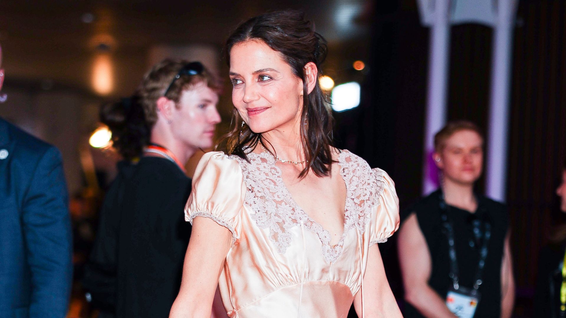 Katie Holmes walks a red carpet wearing a pink satin dress with t-bar heels.