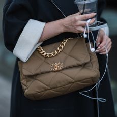 Woman with subtle shimmery nails holding earphones and Chanel handbag - best shimmery nail polishes