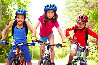 Three children ride their bikes together.