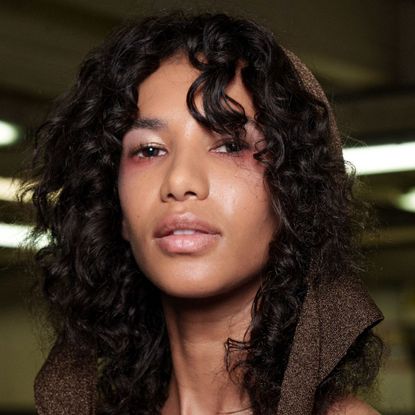 a closeup of a model's face and curly hair backstage at fashion show - best silk bonnets for sleeping in