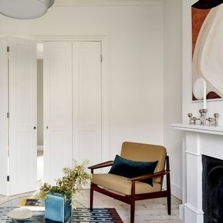 White living room with fireplace, bi-fold doors, abstract artwork, mid-century chair