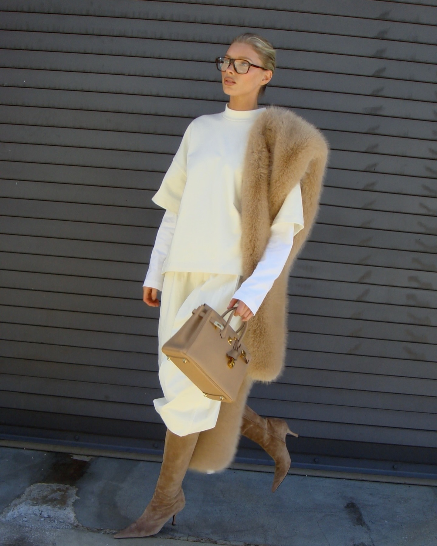 Elsa Hosk wearing a butter yellow sweatshirt and sweatpants with tan boots, a tan fur scarf, and a tan Birkin bag.
