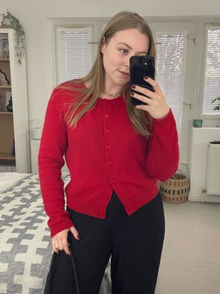 Woman wears red cardigan, black trousers