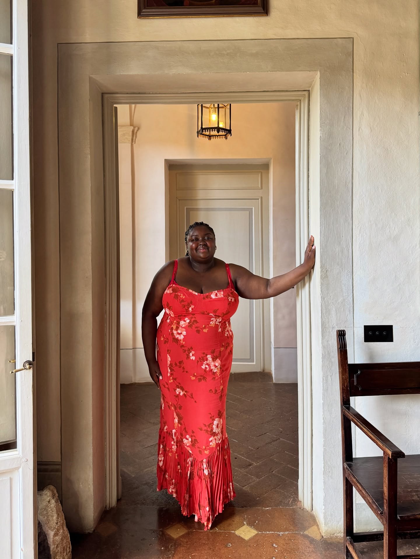 An image of @abimarvel wearing a red floral dress from sustainable fashion brand Reformation.