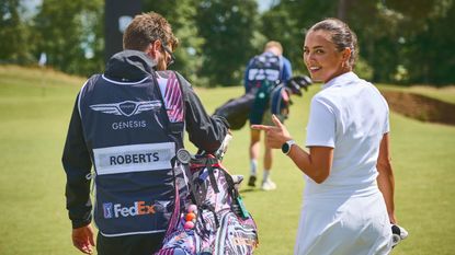 Female golfer points to her caddie with her name on his bib