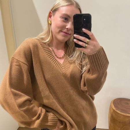 Woman wears camel jumper, gold jewellery