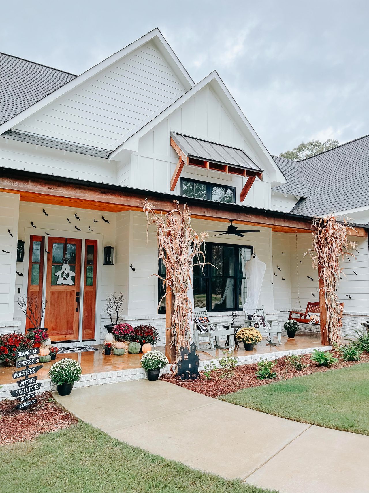 Halloween porch decorated with ghosts, mums and cushions