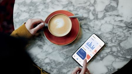 woman doing mobile banking with smartphone while enjoying coffee at marble table