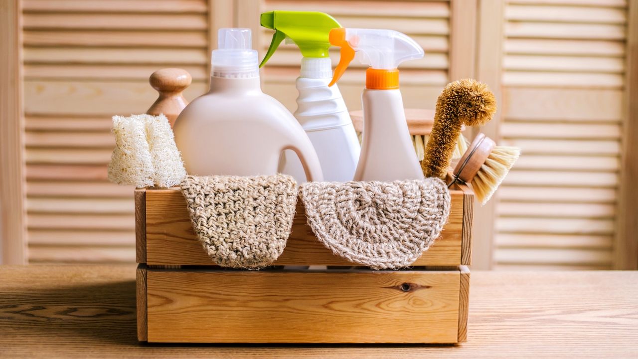 Cleaning eco set for different surfaces in home including bottles, sprays, cloths and brushes in a wooden crate